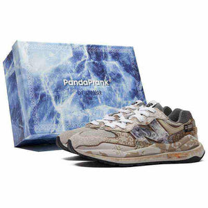 Angled side view of multi-textured New Balance shoes displayed in front of a blue marble shoebox.