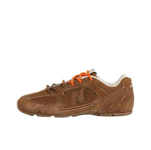 Lateral side view profile of brown suede New Balance running shoes with bright orange laces