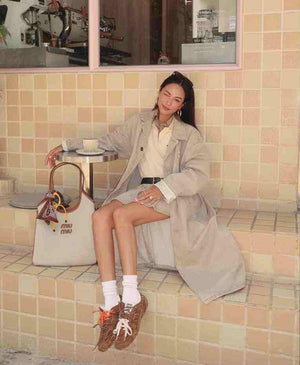 On-feet view of brown suede New Balance x Miu Miu shoes with orange and white double laces.