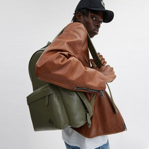 Side view of a man wearing an authentic Coach Westway 32 olive green leather backpack, perfect for back-to-school and casual styling.
عرض جانبي لرجل يرتدي حقيبة ظهر كوتش ويست واي 32 أصلية جلد باللون الزيتي، مناسبة للعودة للمدرسة والإطلالات العصرية.