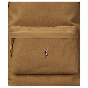Detailed close-up of the front zipped pocket and signature embroidered pony logo on an authentic camel Polo Ralph Lauren backpack.
لقطة قريبة مكبرة للجيب الأمامي ذي السحاب وشعار المهر المطرز المميز على حقيبة ظهر Polo Ralph Lauren أصلية باللون الجملي