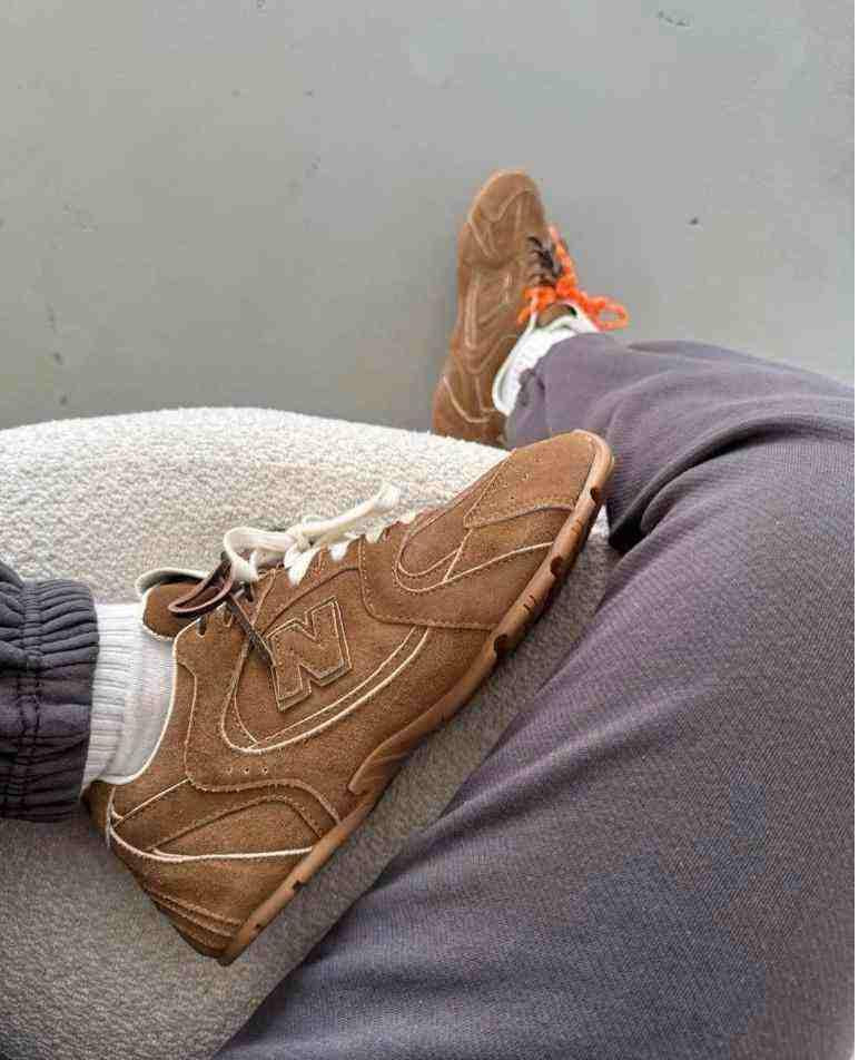 First-person view of brown suede New Balance x Miu Miu shoes worn with grey sweatpants.