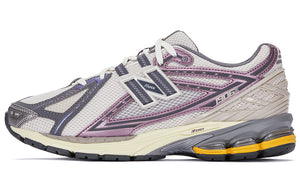Lateral side profile of grey and purple New Balance shoes 1906R model, featuring off-white mesh uppers, metallic mauve and slate grey overlays, N-Lock lacing system webbings, beige heel TPU support cage, and an cream N-ergy cushioned midsole with bright orange heel pods.