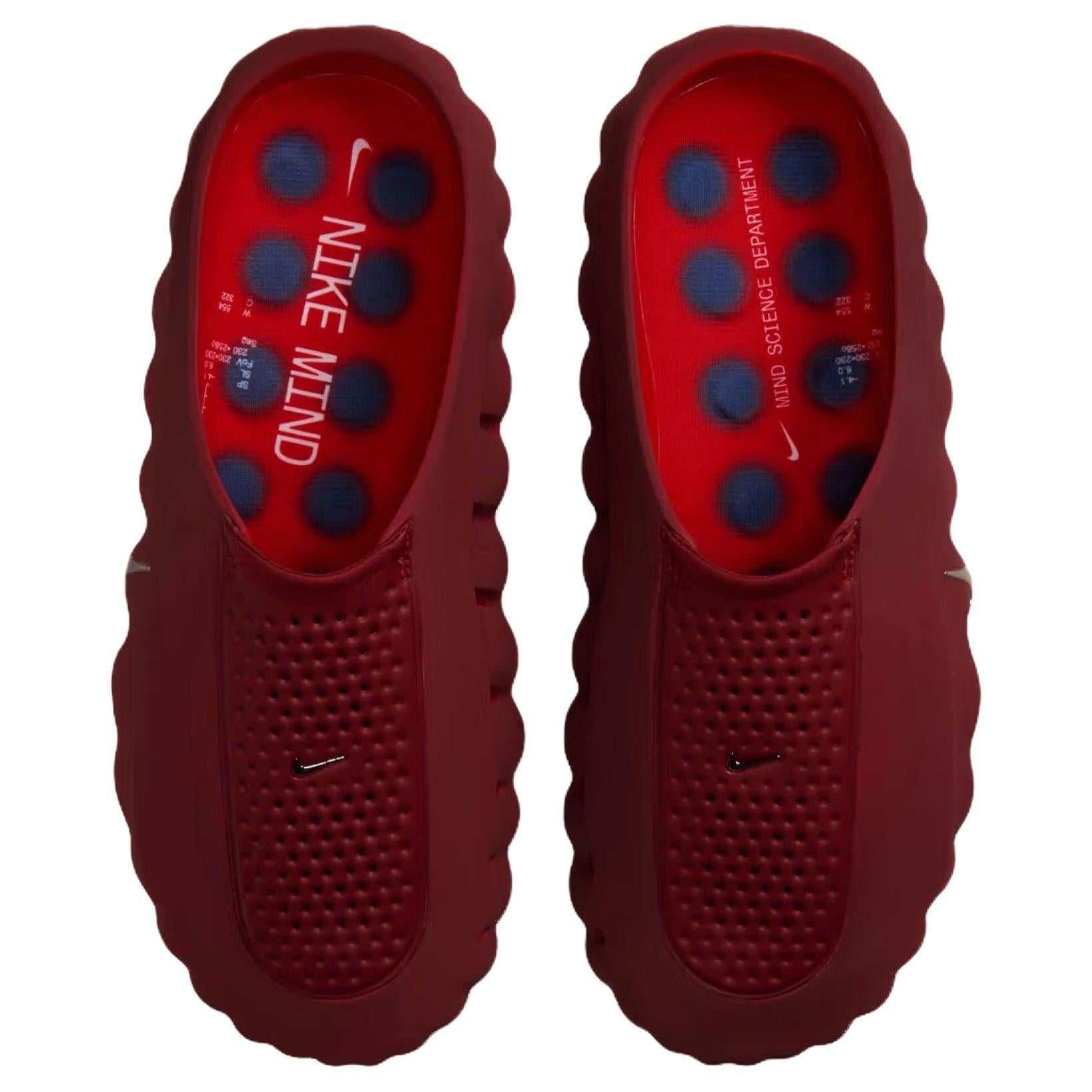 Top-down perspective of a pair of Nike Mind 001 deep red mules, displaying the footbeds with their blue pressure-point design and 'NIKE MIND' branding.