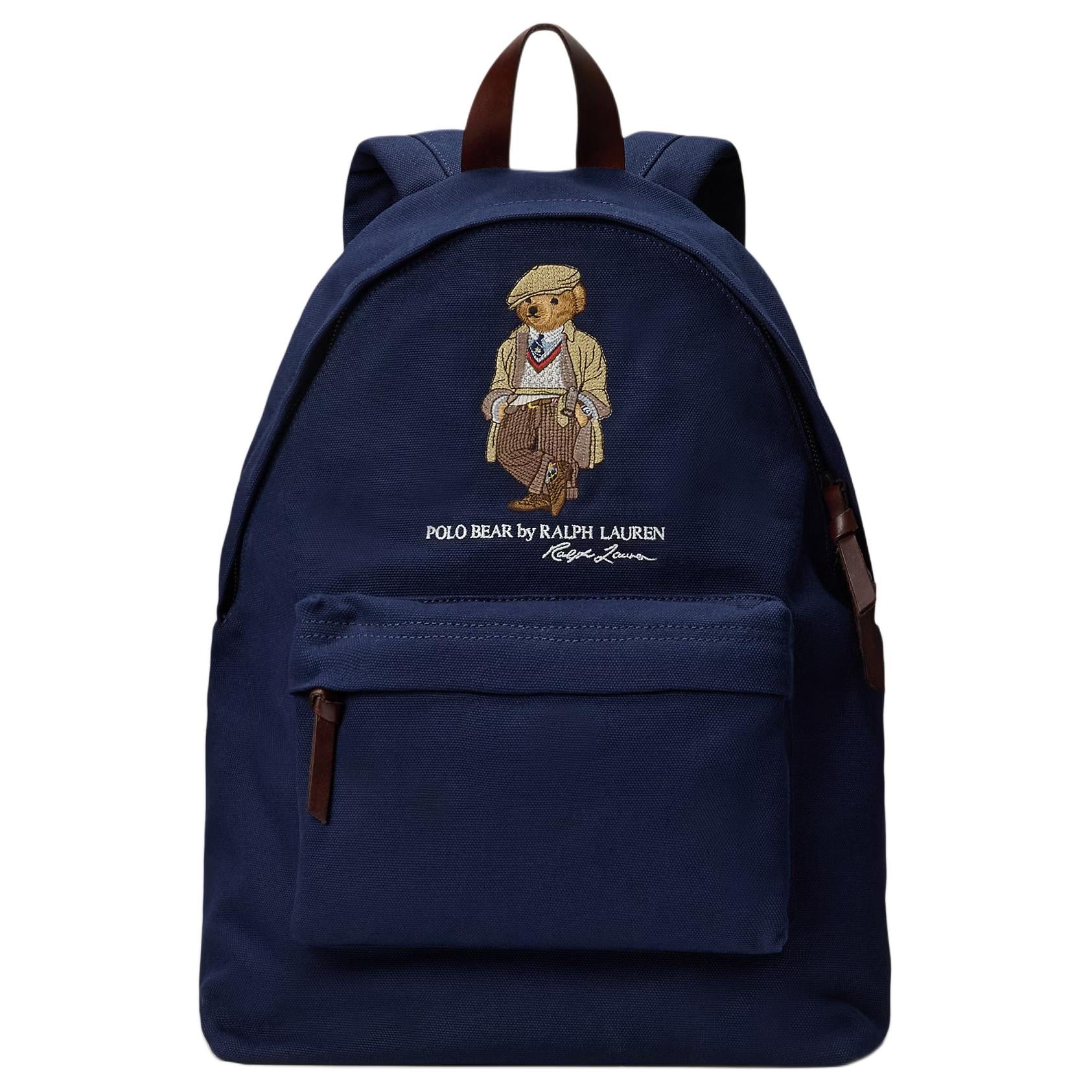 An authentic Ralph Lauren Polo Bear navy blue backpack with a brown leather top handle, leather zipper straps, and embroidered iconic bear, ideal for back-to-school and daily use.

حقيبة ظهر Ralph Lauren Polo Bear كحلي أصلية مع مقبض علوي وأشرطة سحاب من الجلد البني ودب مطرز شهير، مثالية للعودة للمدرسة والاستخدام اليومي.