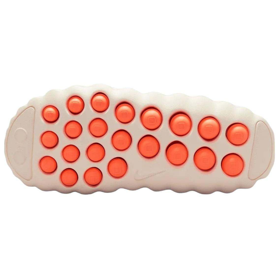 Bottom traction sole view of the Nike Mind 001 off-white, featuring rows of textured apricot orange grip pods for stability.