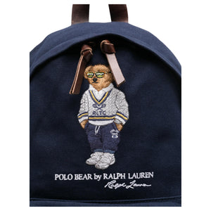 Close-up of the iconic embroidered Polo Bear wearing a sweater and glasses on an original navy Ralph Lauren backpack with brown leather zipper pulls.

لقطة قريبة لتطريز دب بولو الشهير الذي يرتدي سترة ونظارات على حقيبة ظهر رالف لورين أصلية باللون الكحلي مع أشرطة سحاب جلدية بنية.